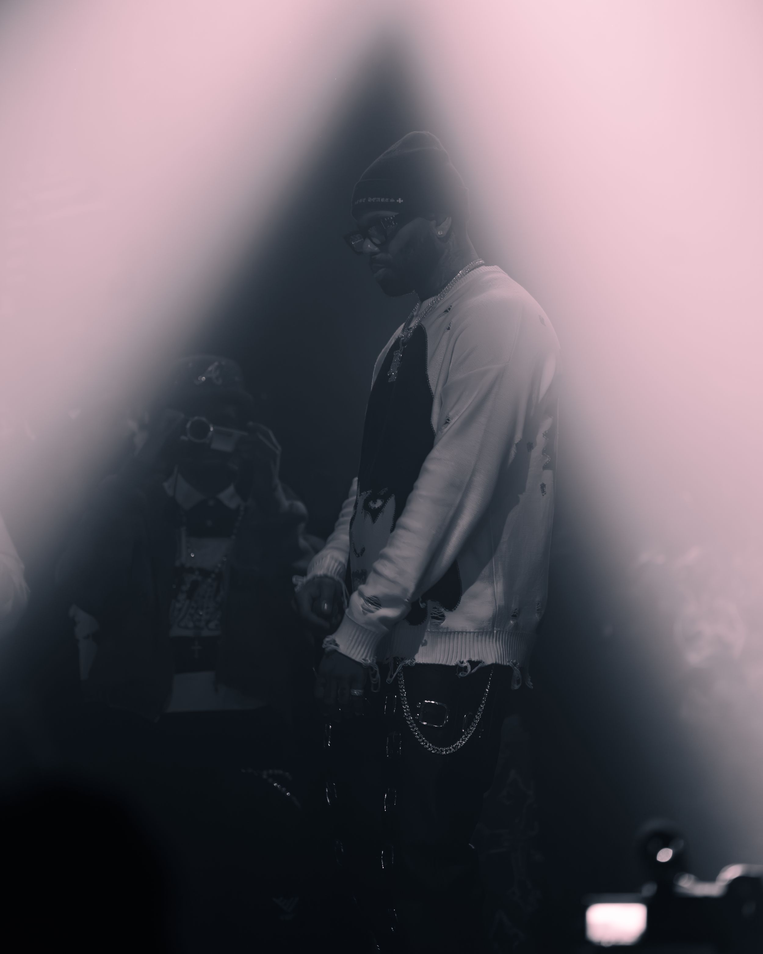 A moody black and white artistic portrait with dark shadows and vignette effect showing a figure in casual attire.