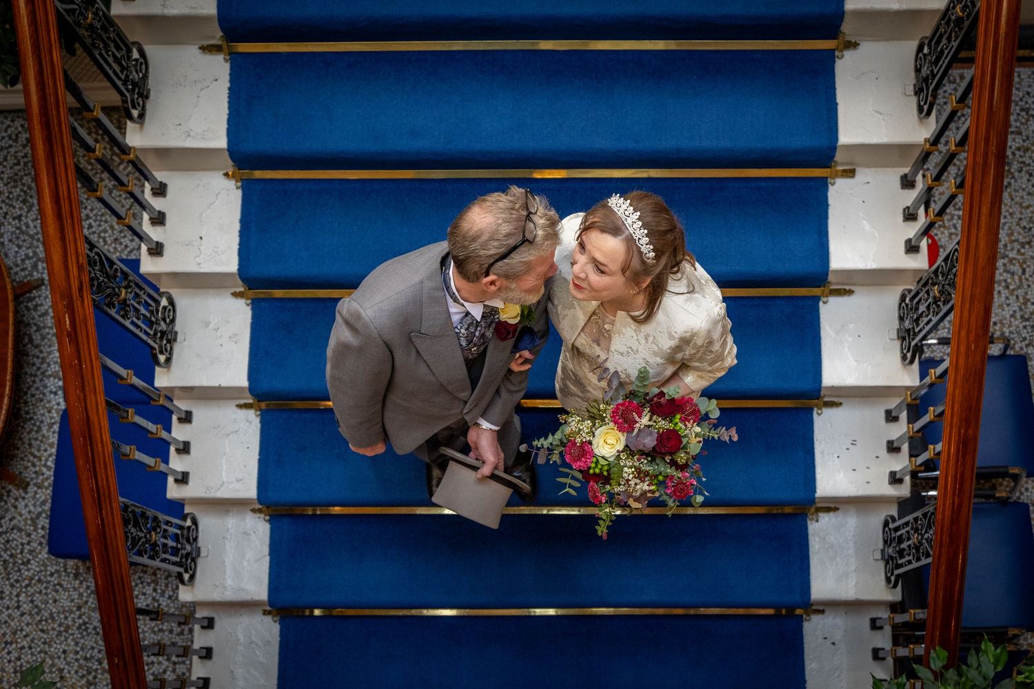 Newly married older couple share a quiet look on Southport Town Hall staircase, relaxed documentary wedding photography