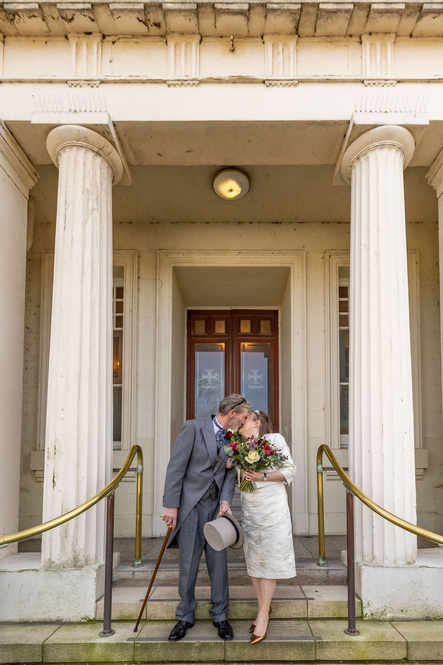 Bride and groom kissing beneath the columns at the entrance of Southport Town Hall, relaxed wedding portrait after the ceremony