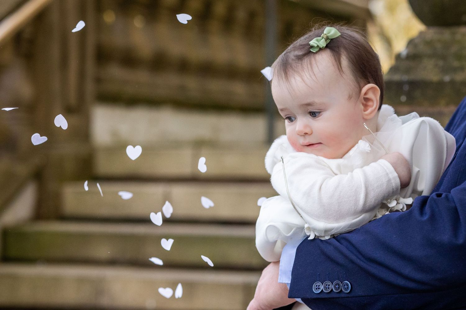 Baby watching heart-shaped confetti fall on the steps of Southport Town Hall after wedding ceremony