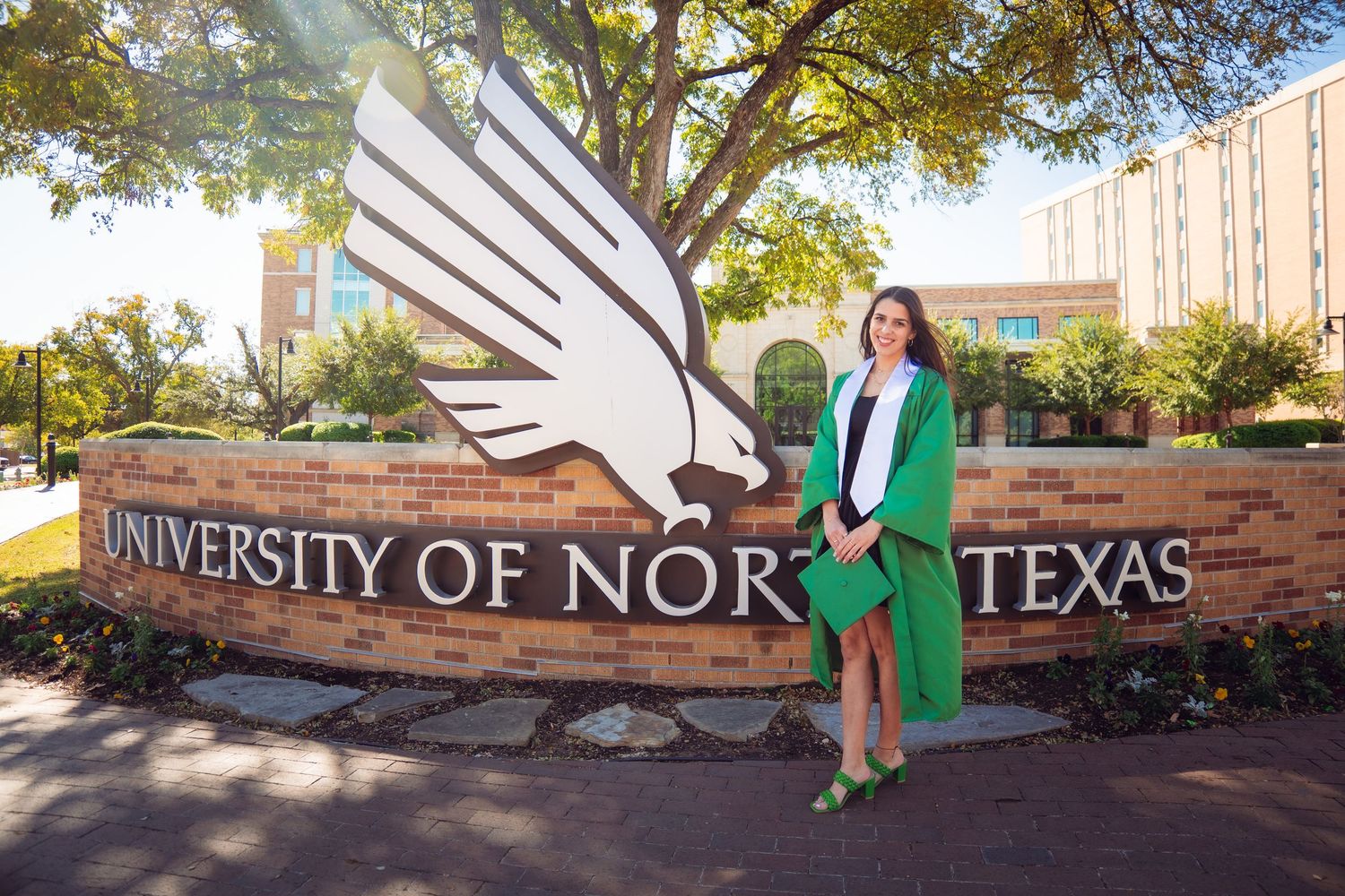 A University of North Texas campus sign surrounded by autumn trees and landscaping.