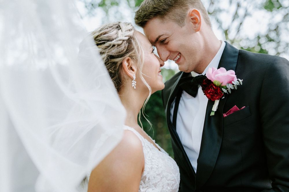 A bride and groom share an intimate moment on their wedding day, with her veil flowing in the breeze.