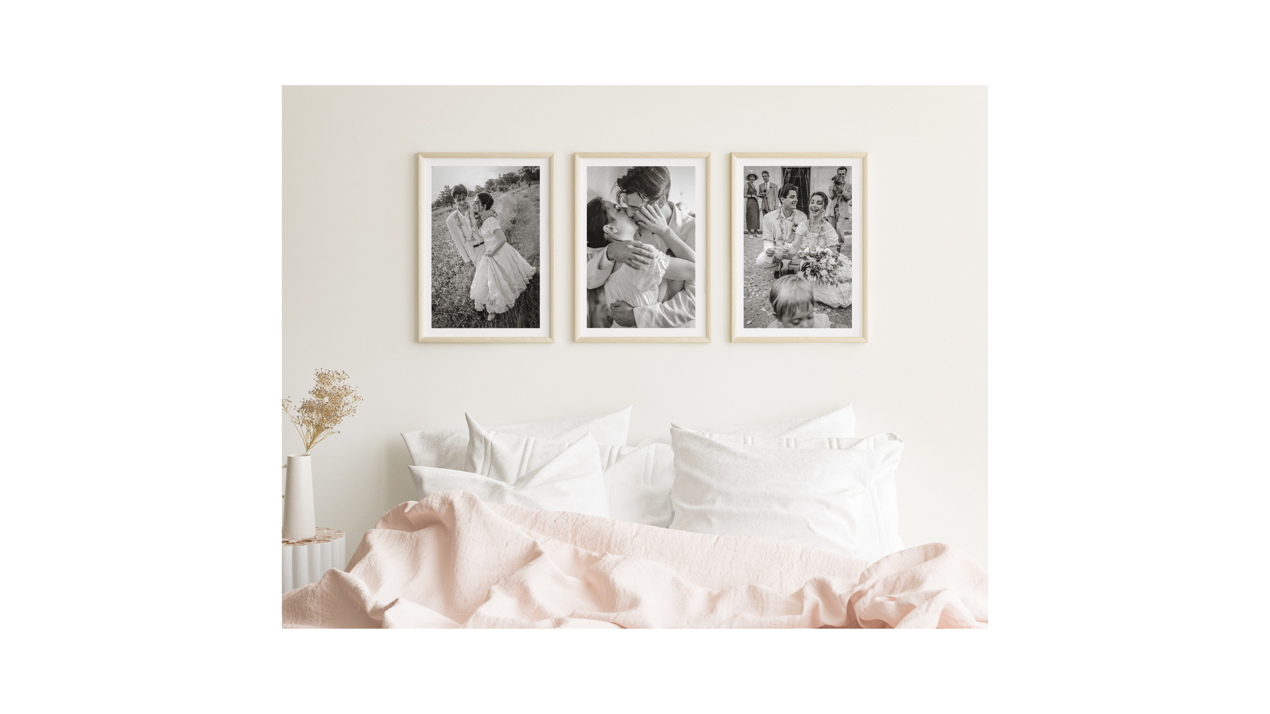 Three black and white wedding photos hung above a bed with soft pink and white bedding.