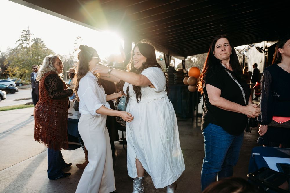 People dancing and celebrating at an outdoor event during golden hour sunset.