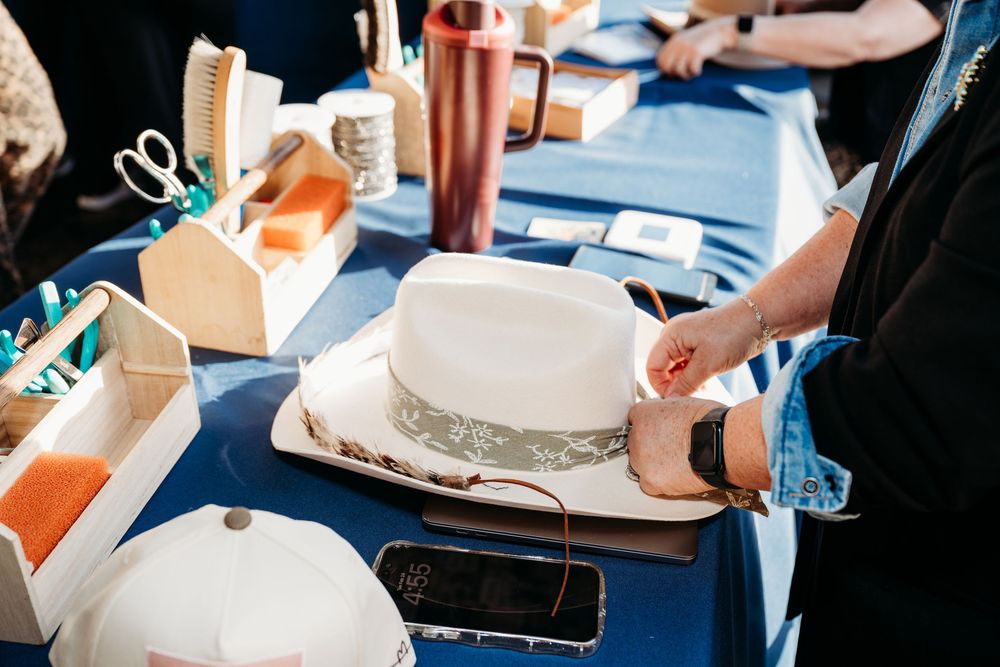 White cowboy hats and takeout boxes arranged on a blue tablecloth at an event.