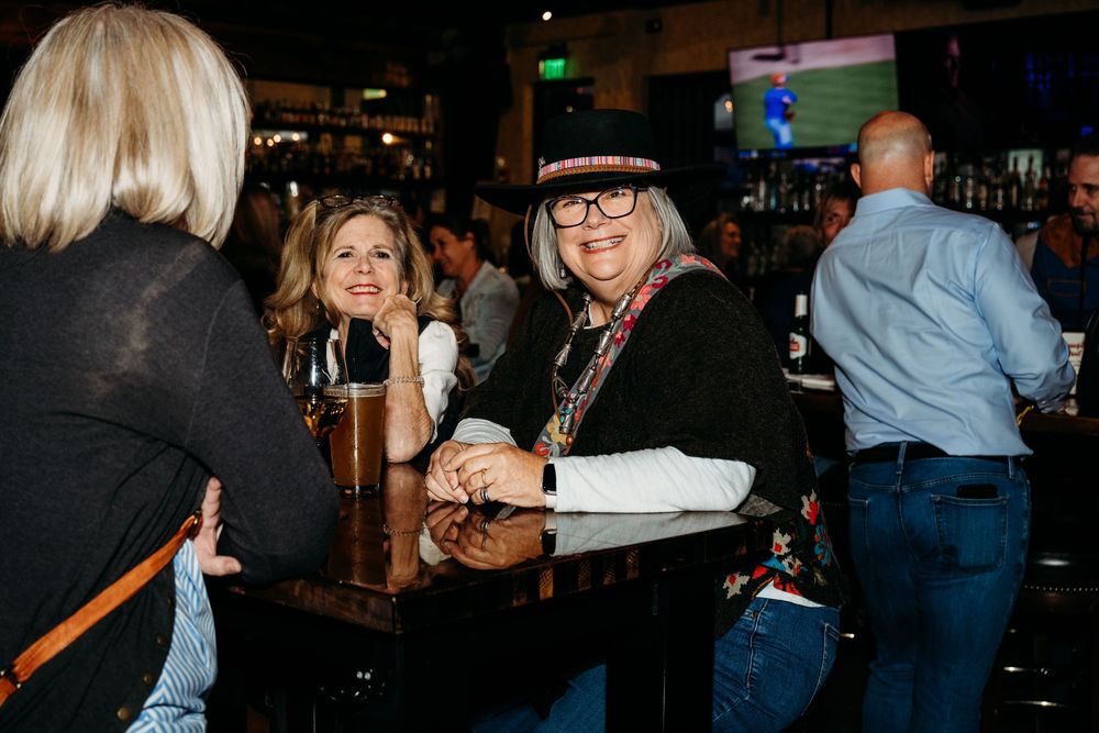 People mingling and socializing at an indoor evening event with dim lighting.
