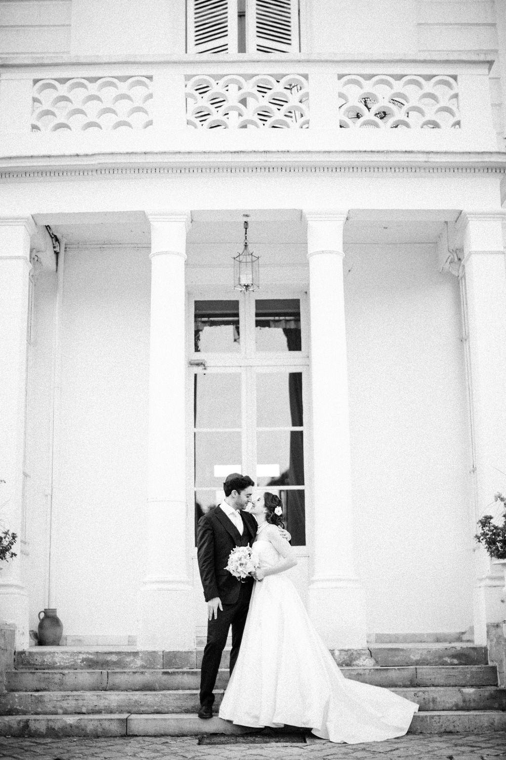 Bride and groom standing together in front of Château Barthélemy near Paris