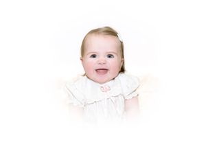 Three adorable babies wearing white outfits smile and laugh while lying next to each other.