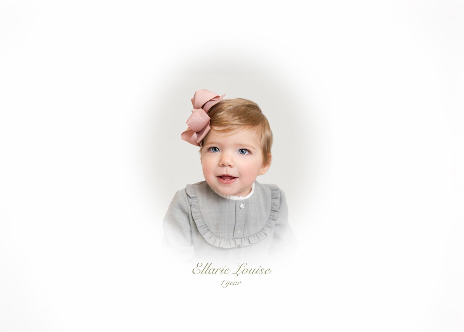 A baby in a gray sweater smiles brightly while sitting against a white background.