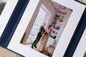 Multiple framed photographs hang in a gallery-style arrangement on a white wall with dark frames and matting.