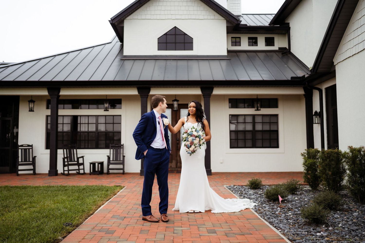 A wedding couple poses at different angles in front of a modern white building with architectural details.