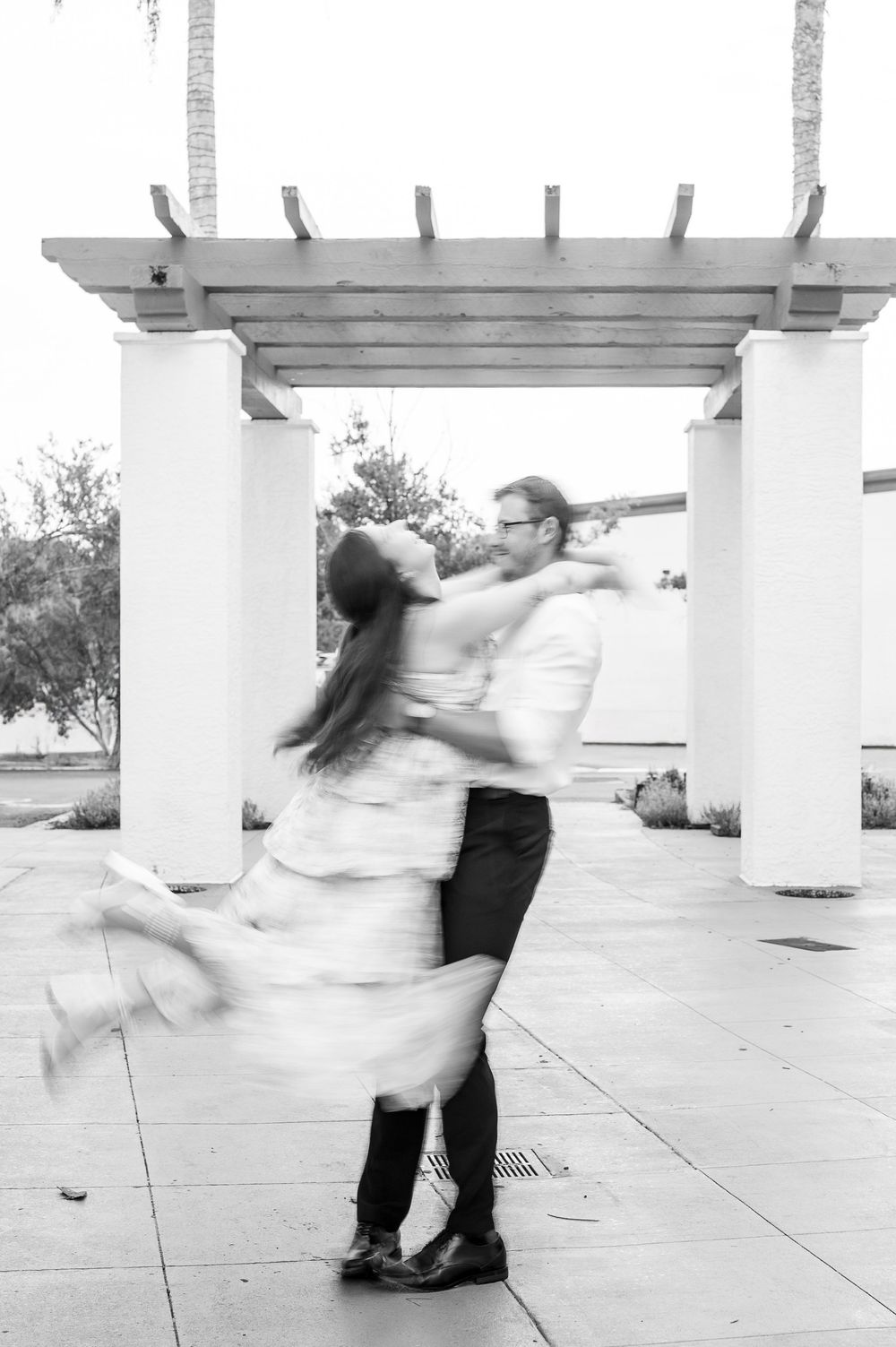 A series of black and white photos showing two dancers performing a dramatic spinning dance movement under white columns.