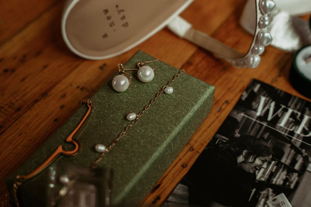Pearl bridal jewelry set displayed on green gift box on wooden table.