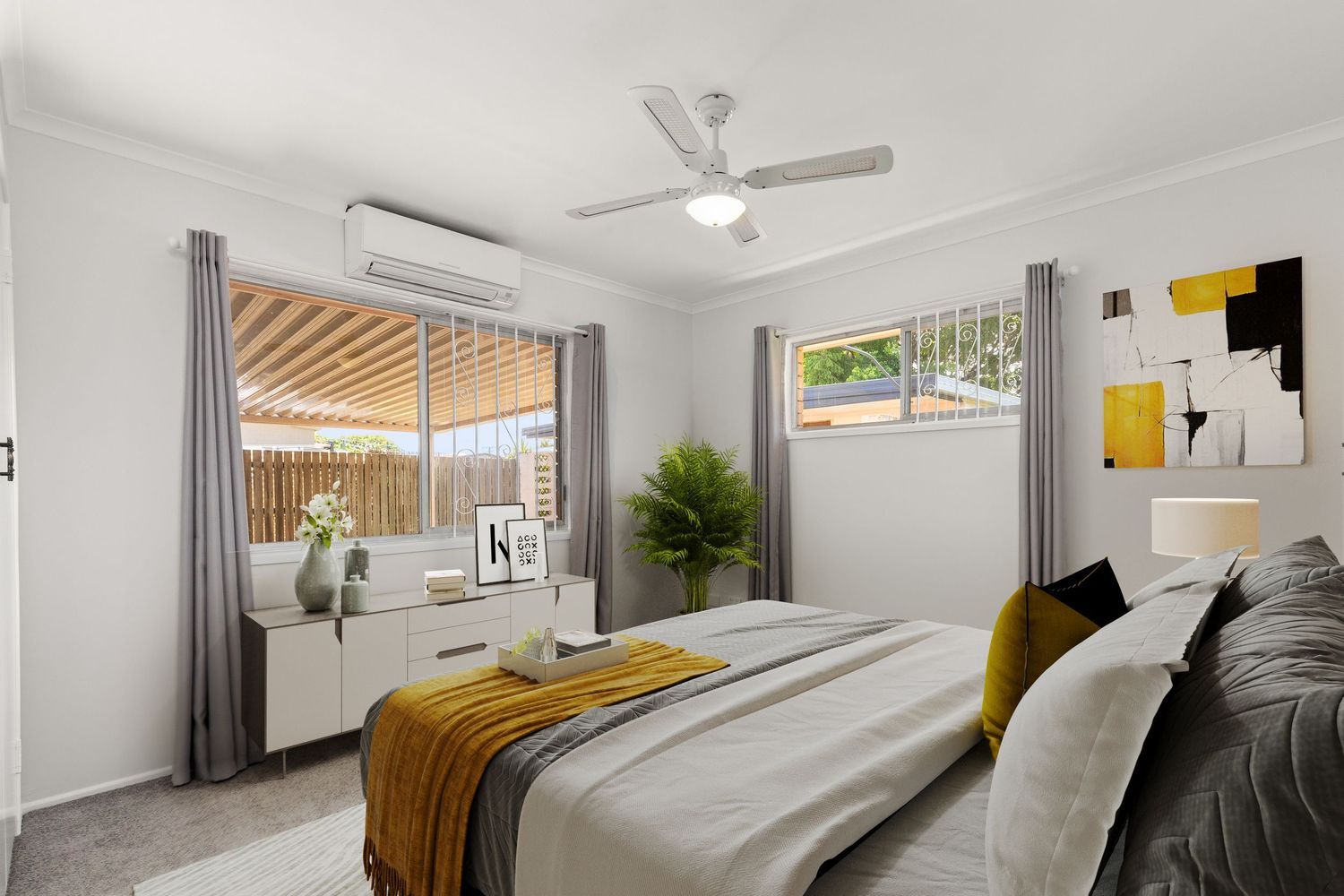 Stylish bedroom with air conditioning, ceiling fan, grey curtains, and yellow accents.