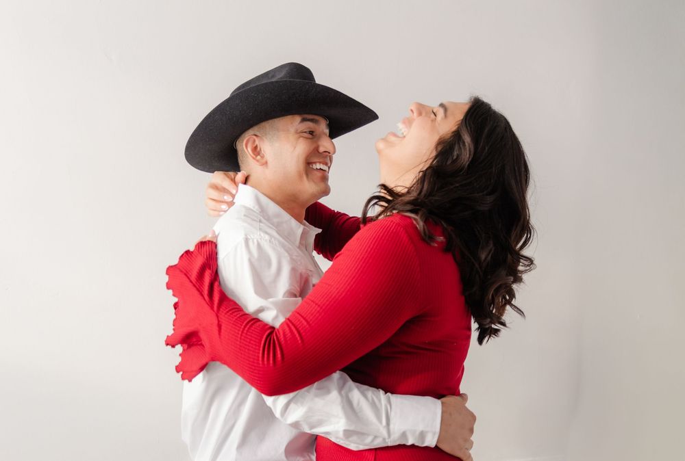 A couple wearing red and white outfits dancing together in a studio setting against a white background.