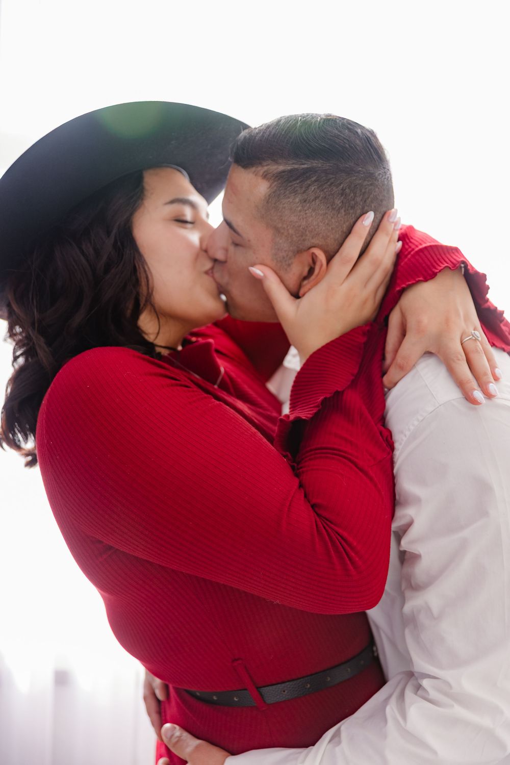 A romantic couple in red and white share a passionate kiss while embracing.