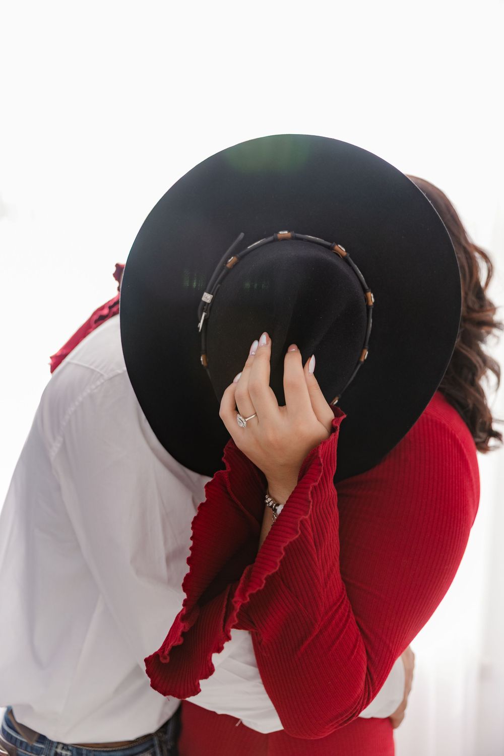 Multiple shots of someone holding a black hat while wearing a red sweater and white shirt.