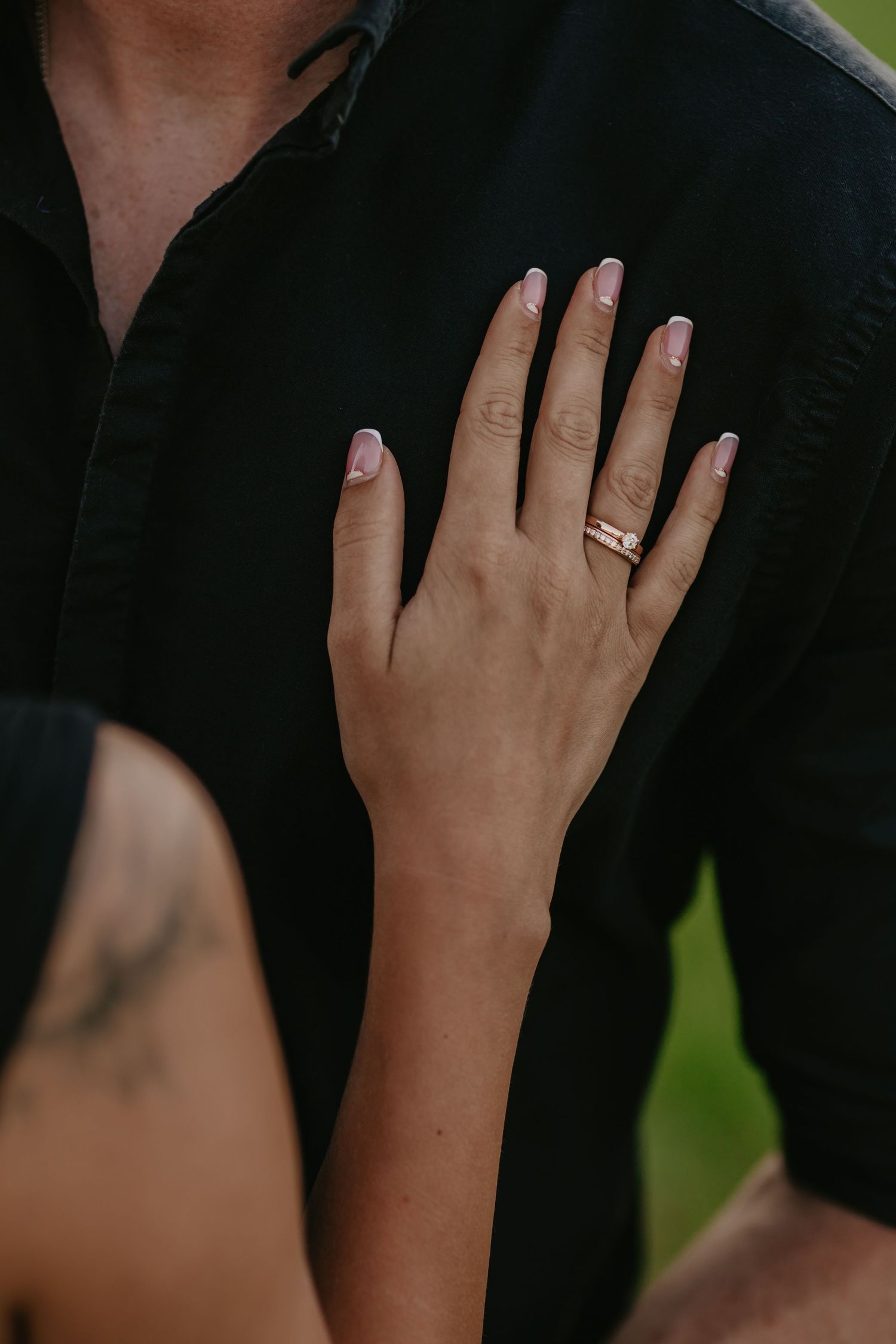Detailný záber na zásnubný prsteň a nežné gesto počas párového fotenia, romantická fotografia plná citu.