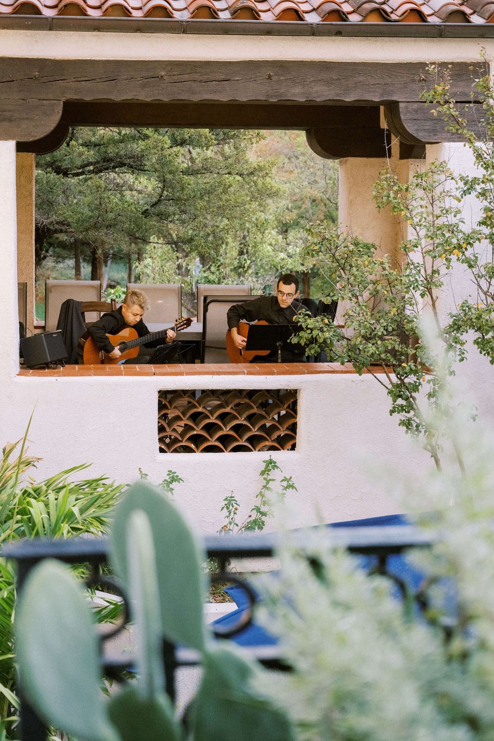 Two guitarists play music on a balcony overlooking the lush gardens at El Sueno during a reception.