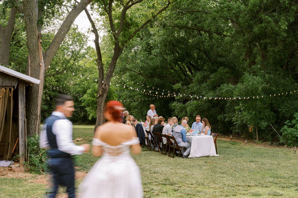 Bride and Groom walk towards their guests seated for dinner in a small, intimate wedding at The Barn at the Woods in Edmond.