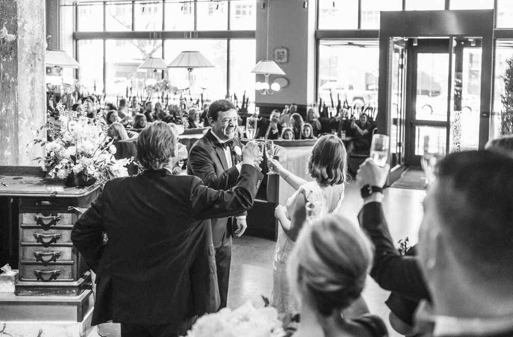 A bride and groom surrounded by guests give a toast at the end of their nuptials. Mary Eddy's restaurant turned into wedding venue.