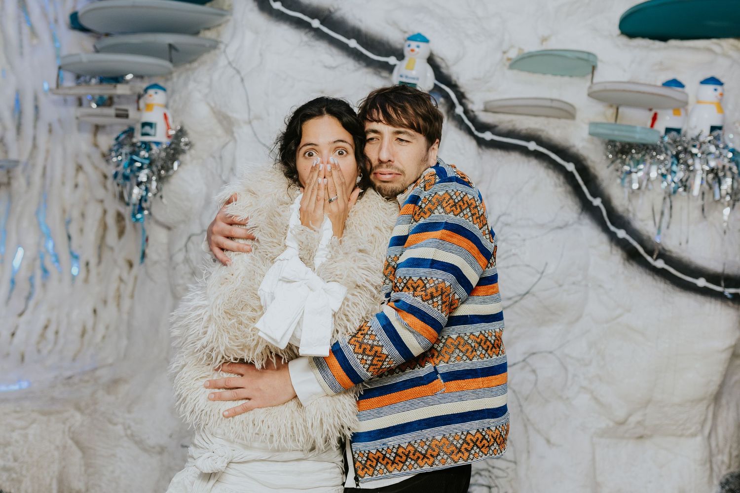 Two people share joyful moments together in a winter setting with snowy white background.