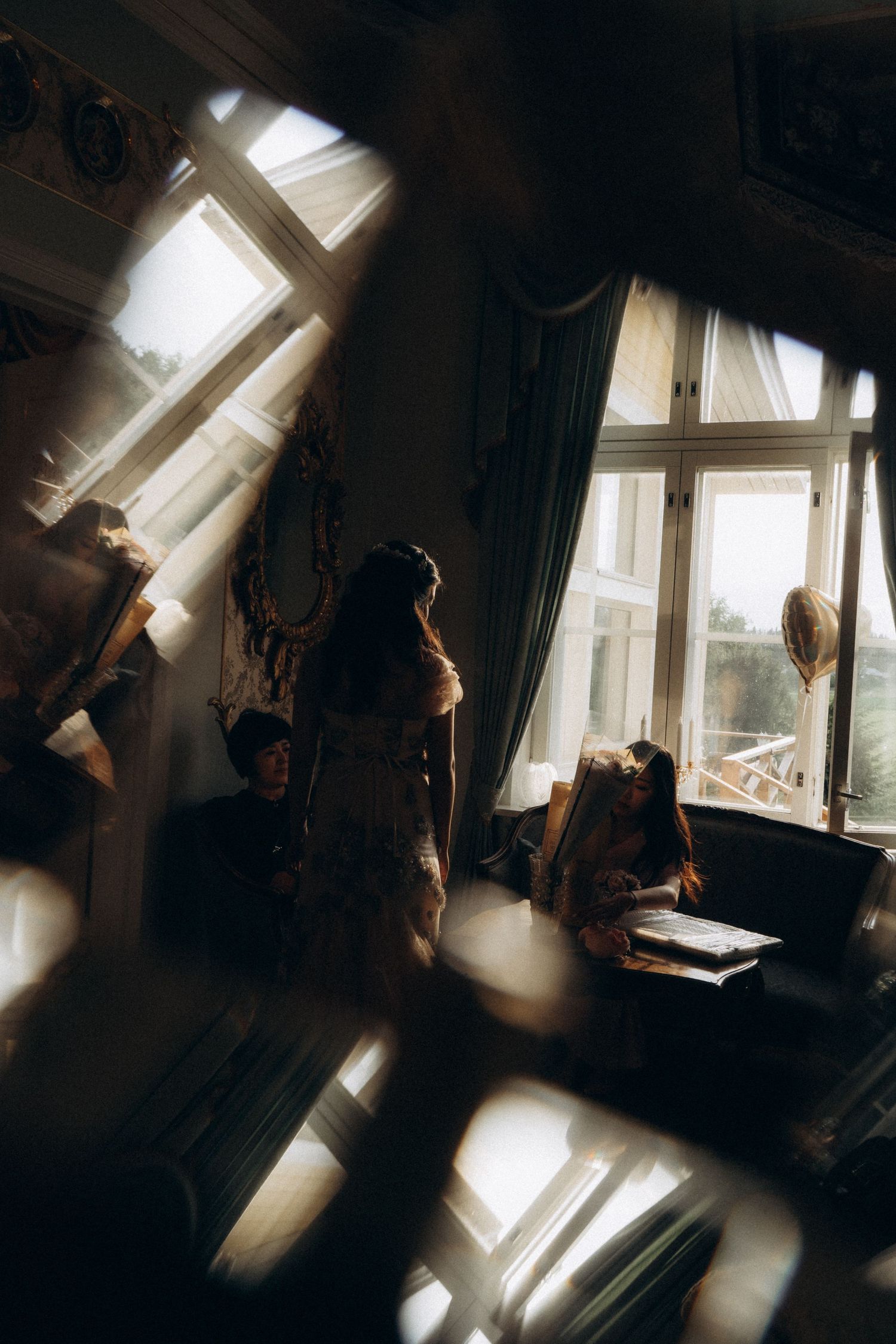 artistic silhouette of bride and bridesmaids in window light moody cinematic wedding photography historic manor interior Finland