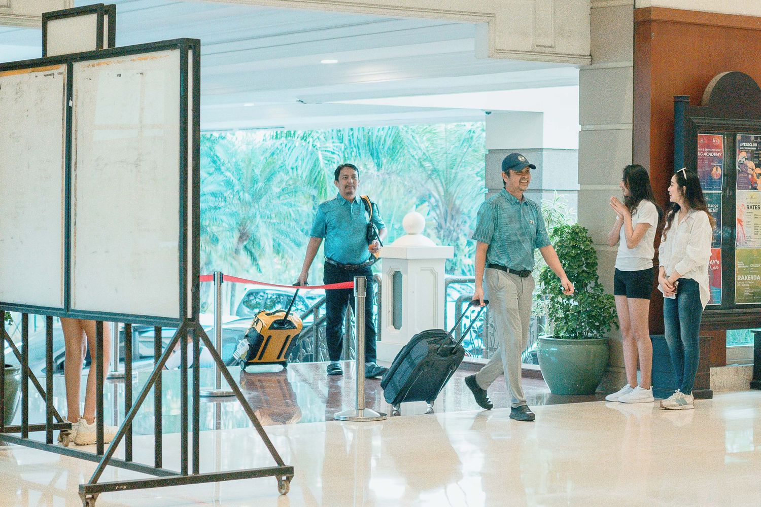 People walking through a bright modern shopping mall interior with glass storefronts and retail displays.
