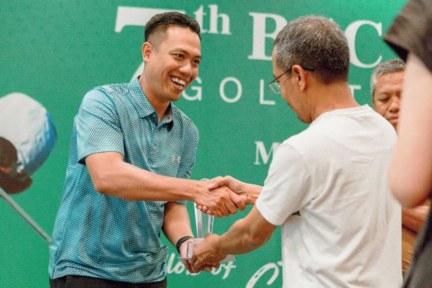 People interacting at a business event with a green branded backdrop displaying BGC logo.