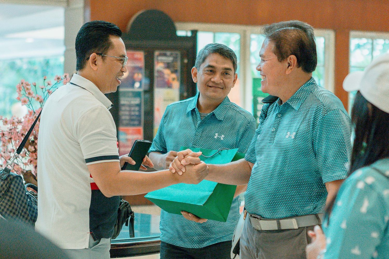 Group of people in turquoise shirts having a business discussion in an office setting.
