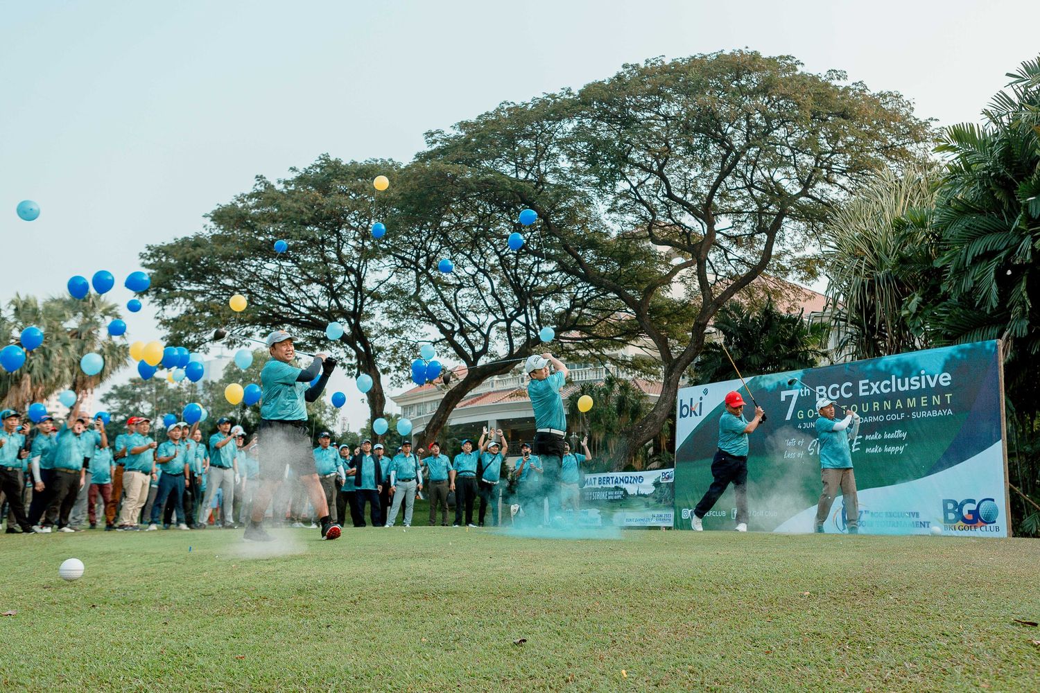 Panoramic view of people gathered on a grassy hill under trees during an outdoor event.