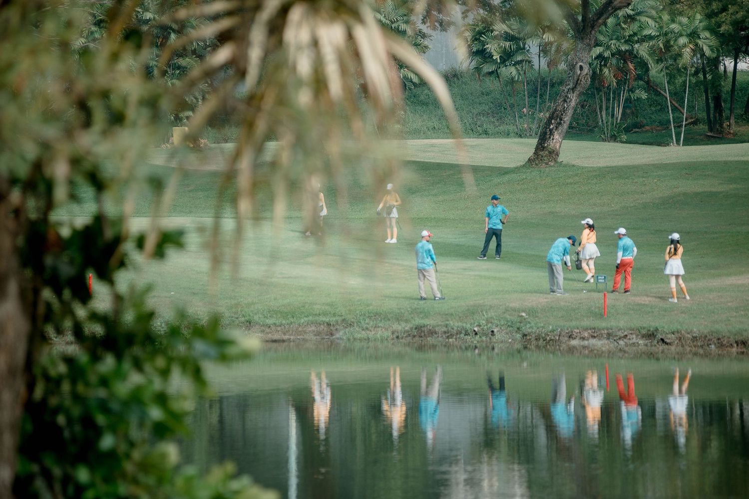 Golfers practicing their putting skills on a scenic green course with trees in the background.