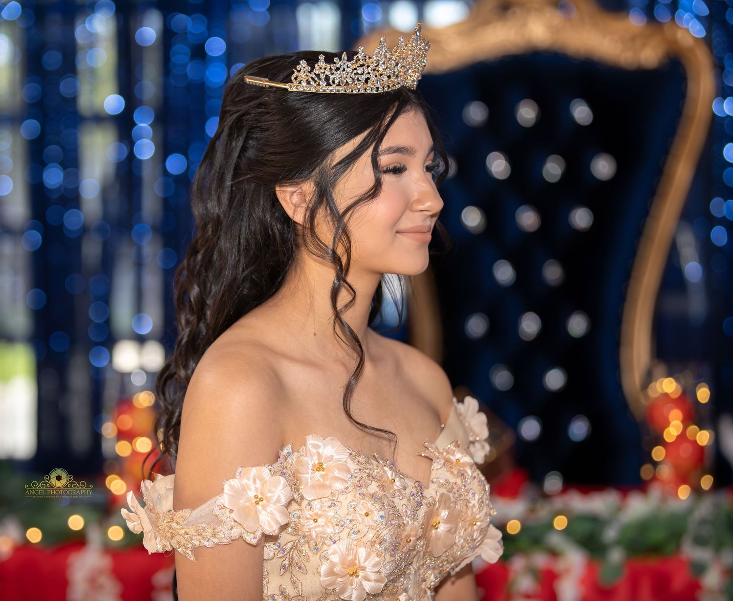 A person in an elegant white lace wedding dress poses in front of a sparkling blue bokeh background.