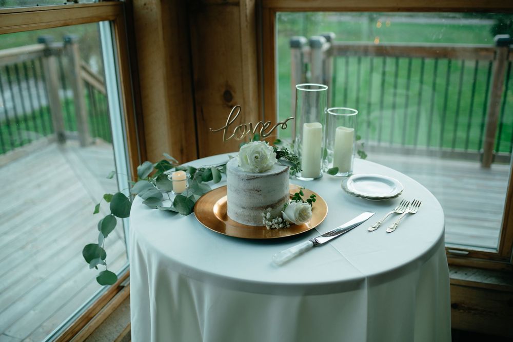 A cozy coffee shop interior with wooden tables and green plants by large windows creating a warm atmosphere.
