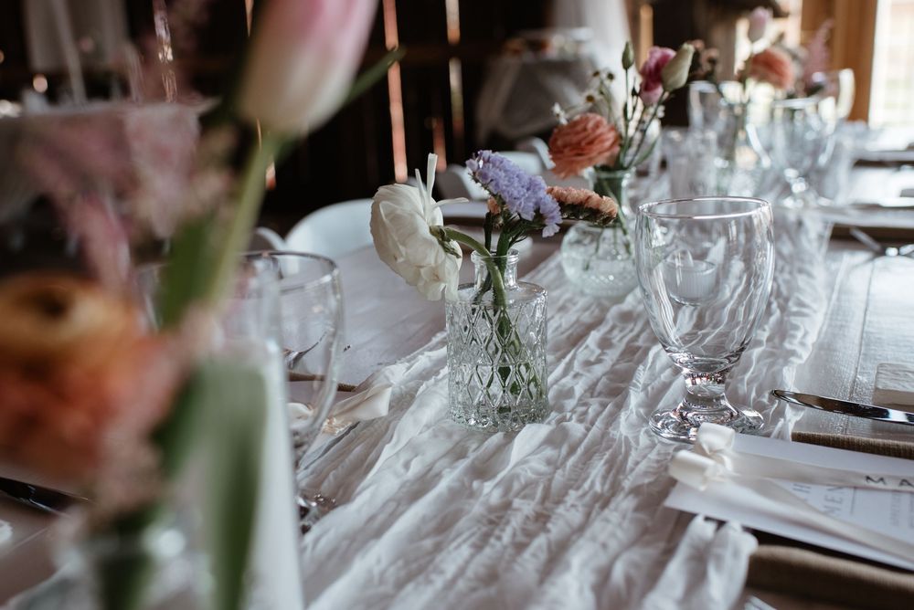 Elegant table setting with crystal glassware and floral arrangements in muted tones for a wedding reception.