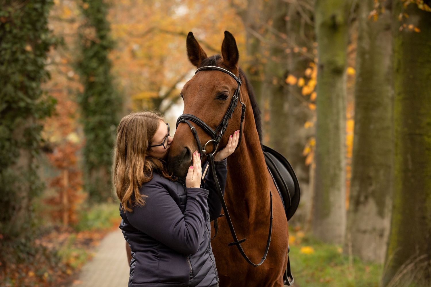 Autumn forest scene with horses and riders enjoying a peaceful trail ride.