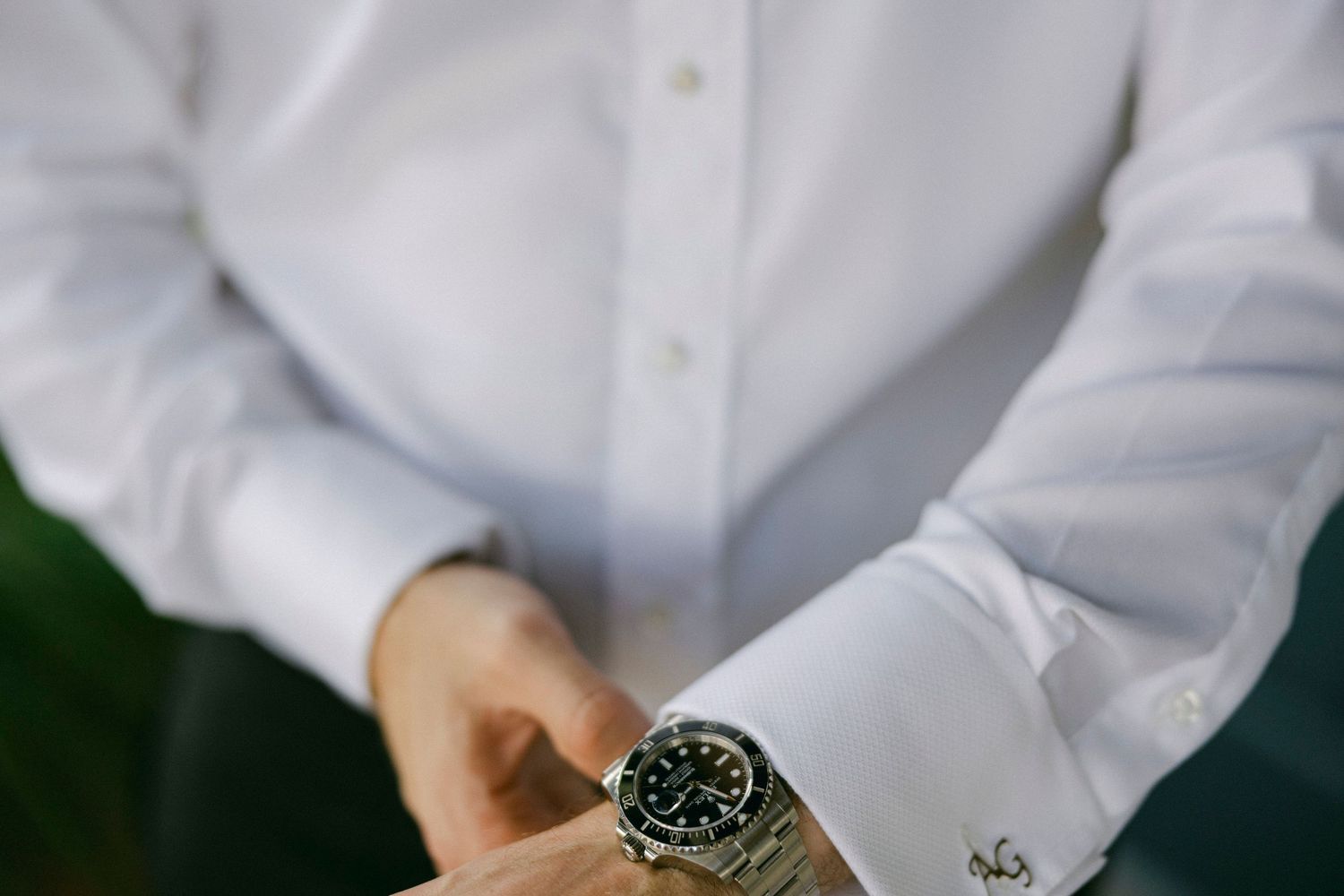 Professional hands adjusting a luxury watch dial in a bright white setting.