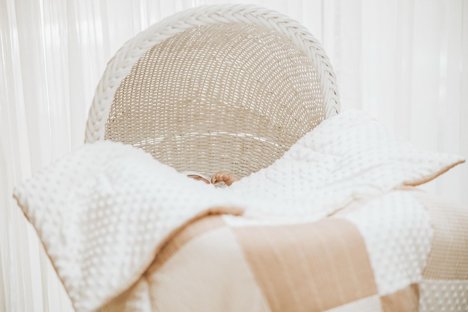 White knit blanket and textured throw pillows arranged on a neutral colored couch in soft natural lighting.