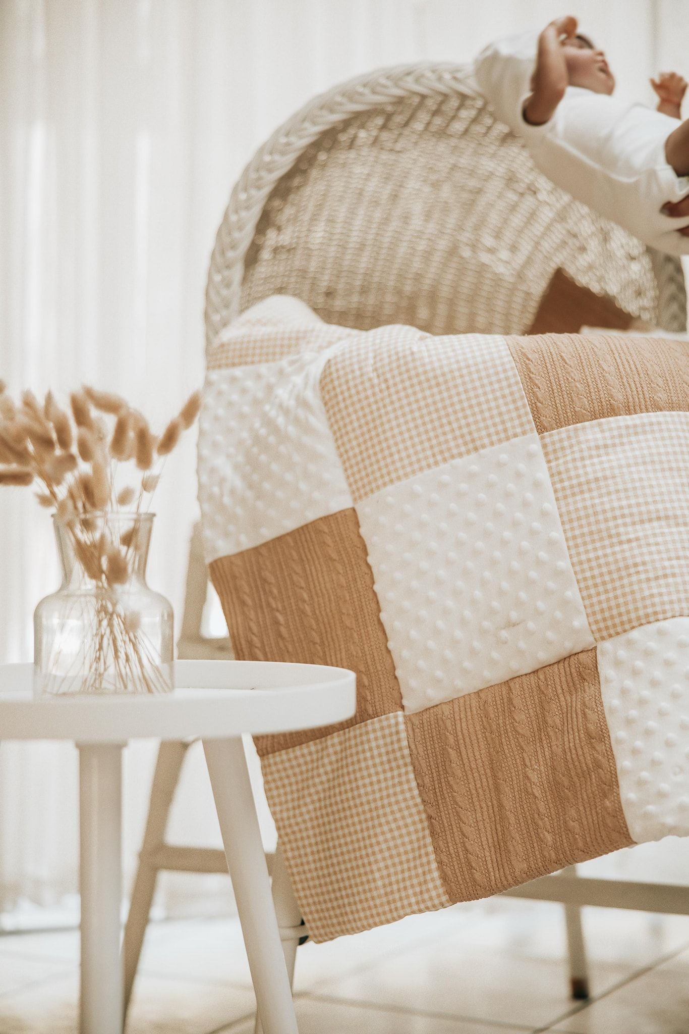 Close-up view of neutral beige and white textured bedding with minky dot fabric and gingham patterns in soft lighting.