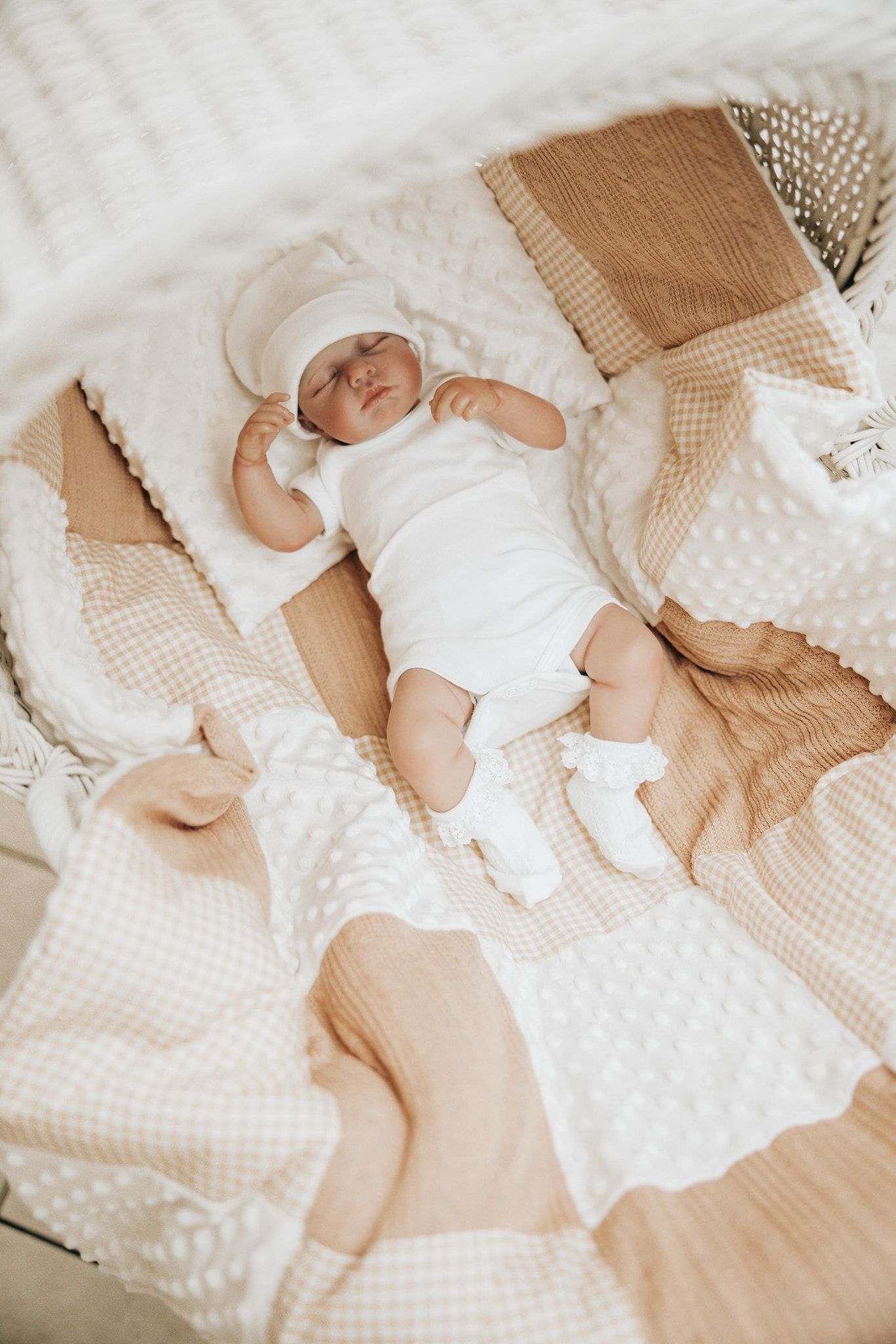 Sleeping baby in white onesie lying on textured beige and white bedding in multiple angles.