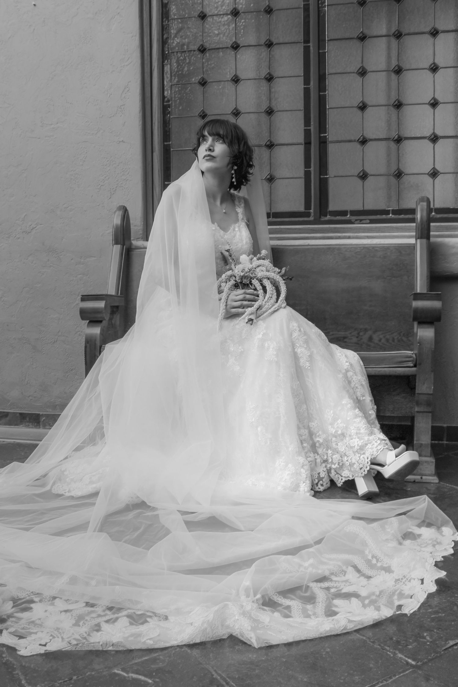 A bride in a white lace wedding dress sits gracefully with a floral bouquet in a series of black and white portraits.