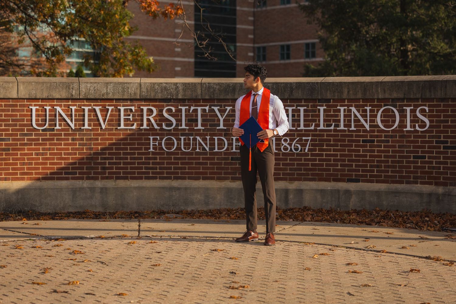 Graduating student at UIUC standing in front of University of Illinois sign