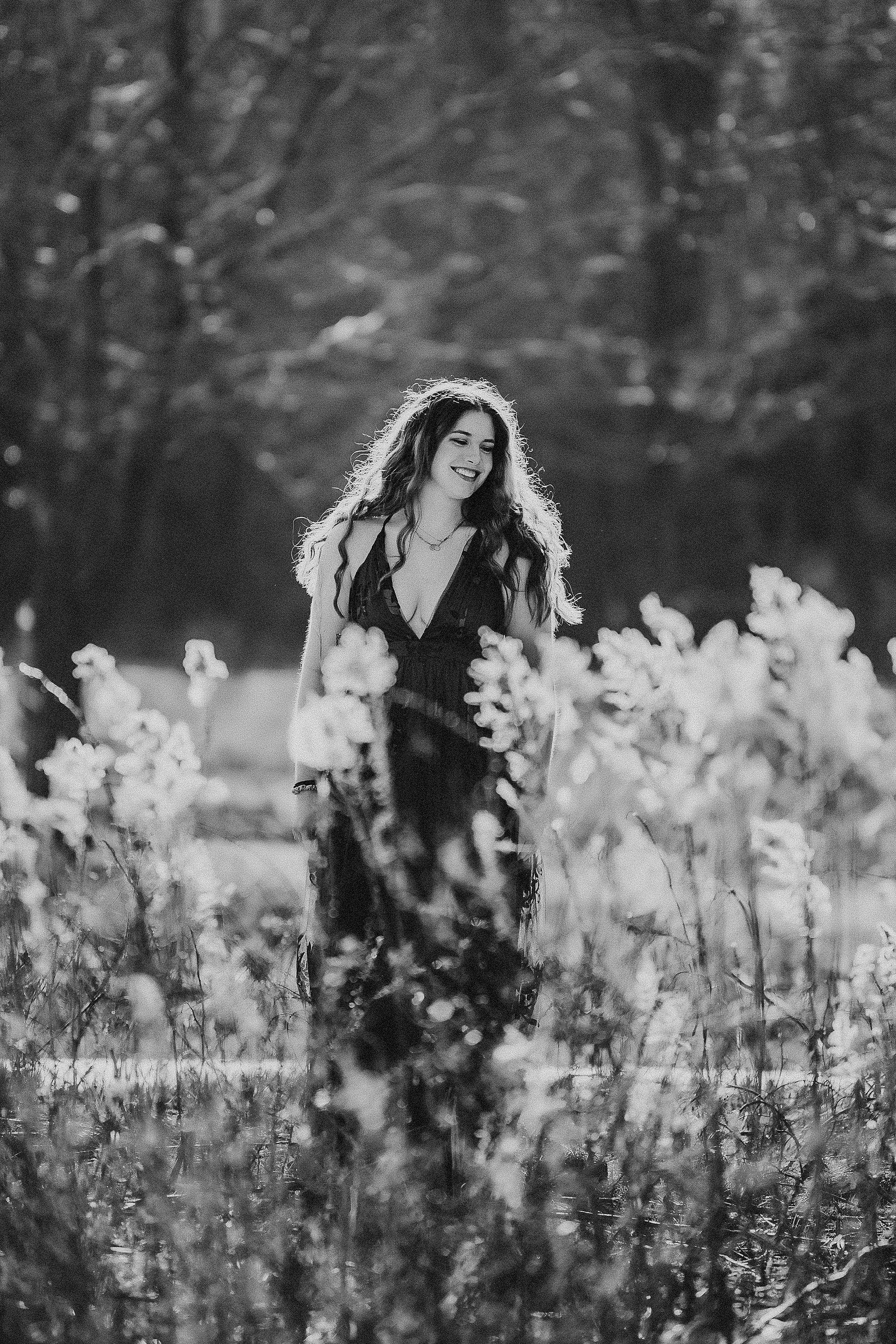 Black and white artistic portrait of someone joyfully posing in a wildflower meadow on a sunny afternoon.
