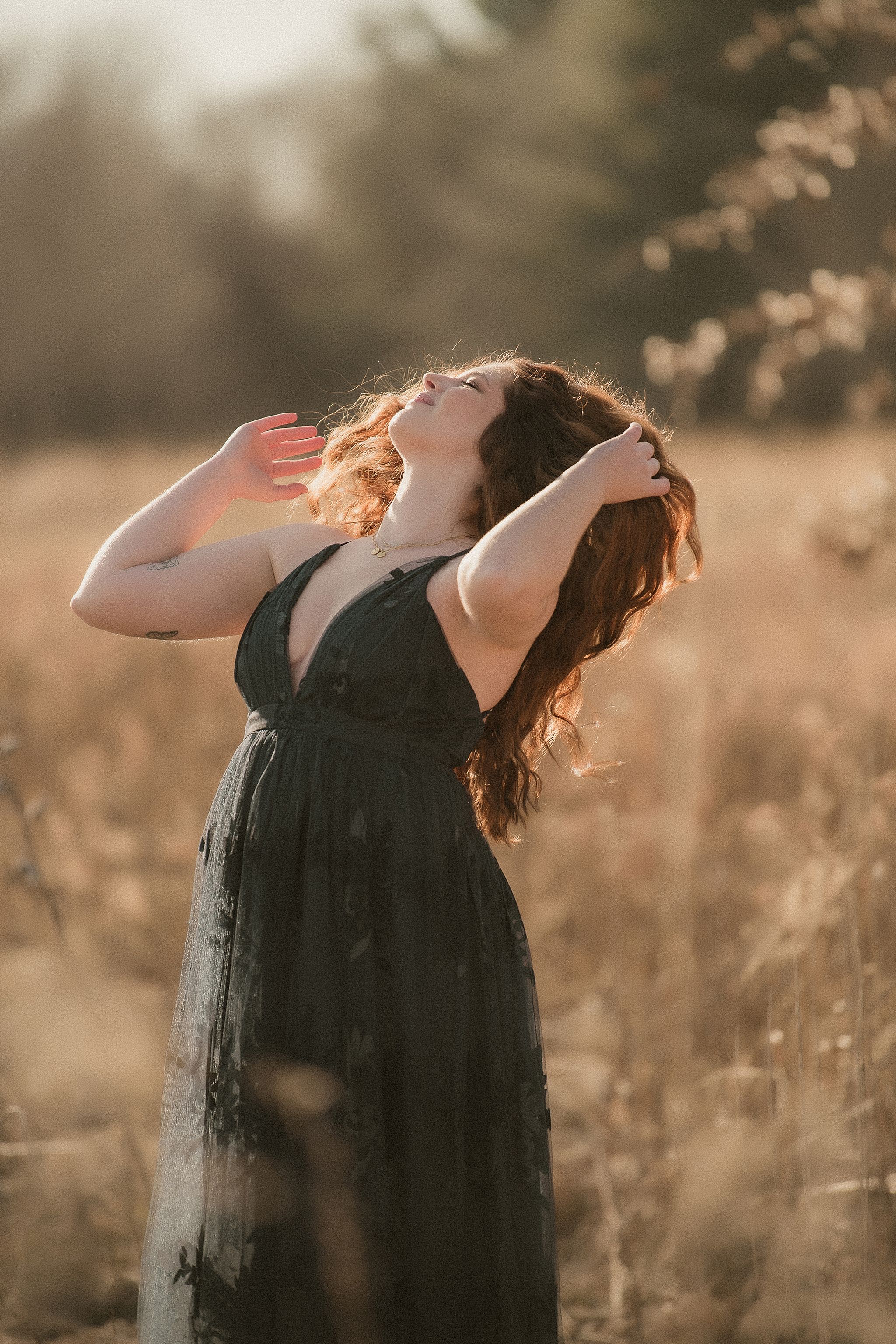 A person in a black dress stands in a golden field at sunset with their head tilted back in four sequential photos.