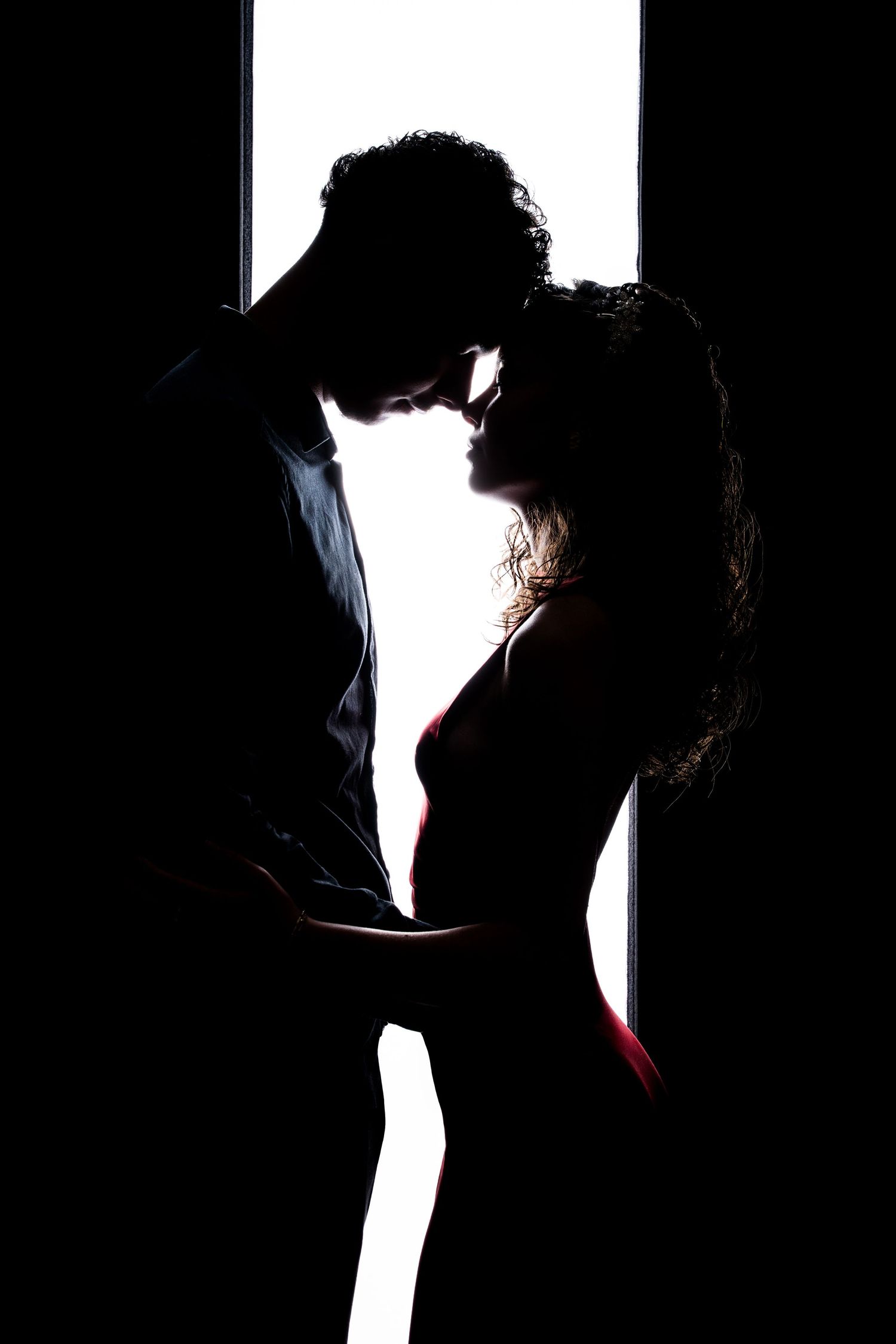 Dramatic silhouette of a romantic couple in intimate pose against bright backlighting.