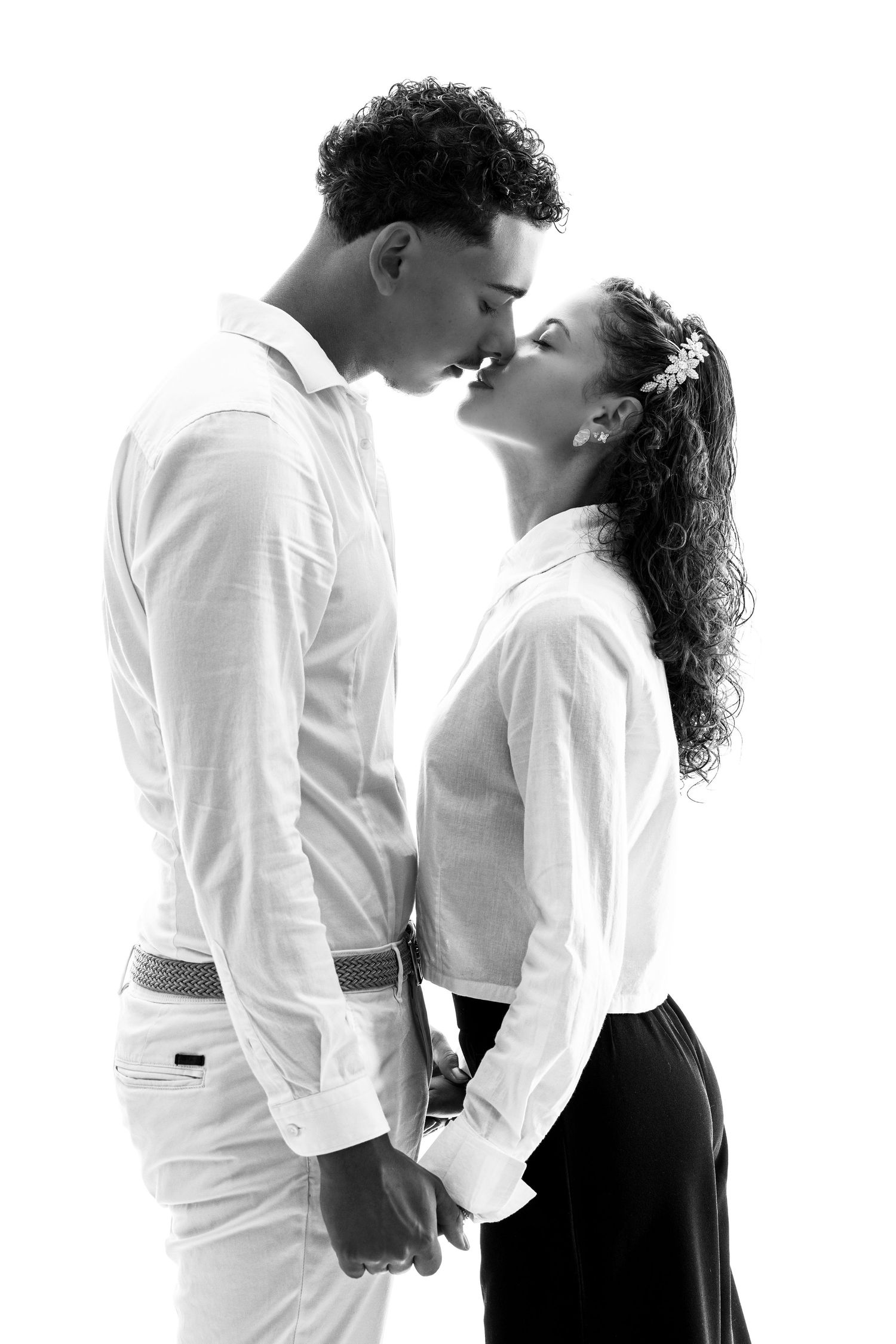 Four romantic black and white photographs show a couple in white and black clothing embracing in intimate poses.