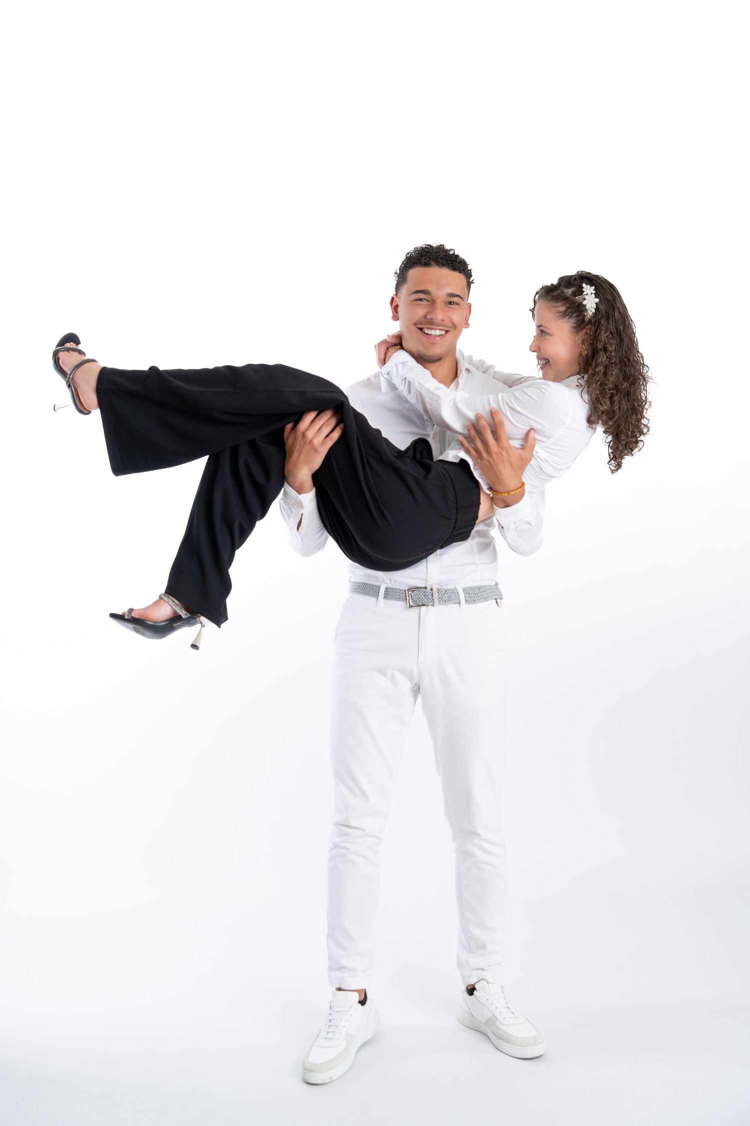 Dancers in matching white outfits perform synchronized dance moves against white background.
