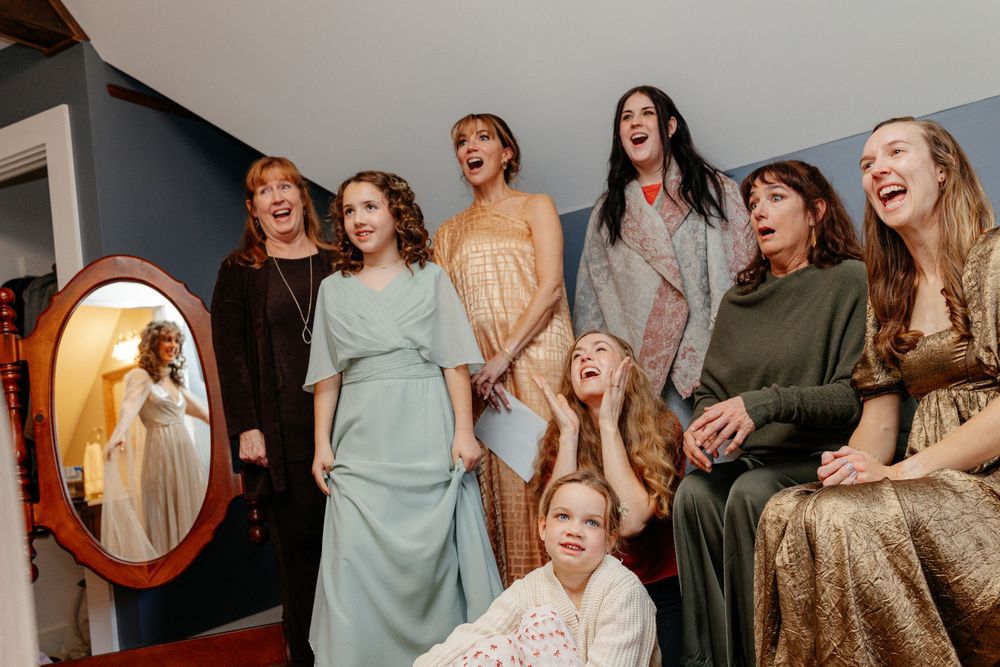 Joyful bride and bridesmaids laughing together while getting ready before the wedding ceremony.