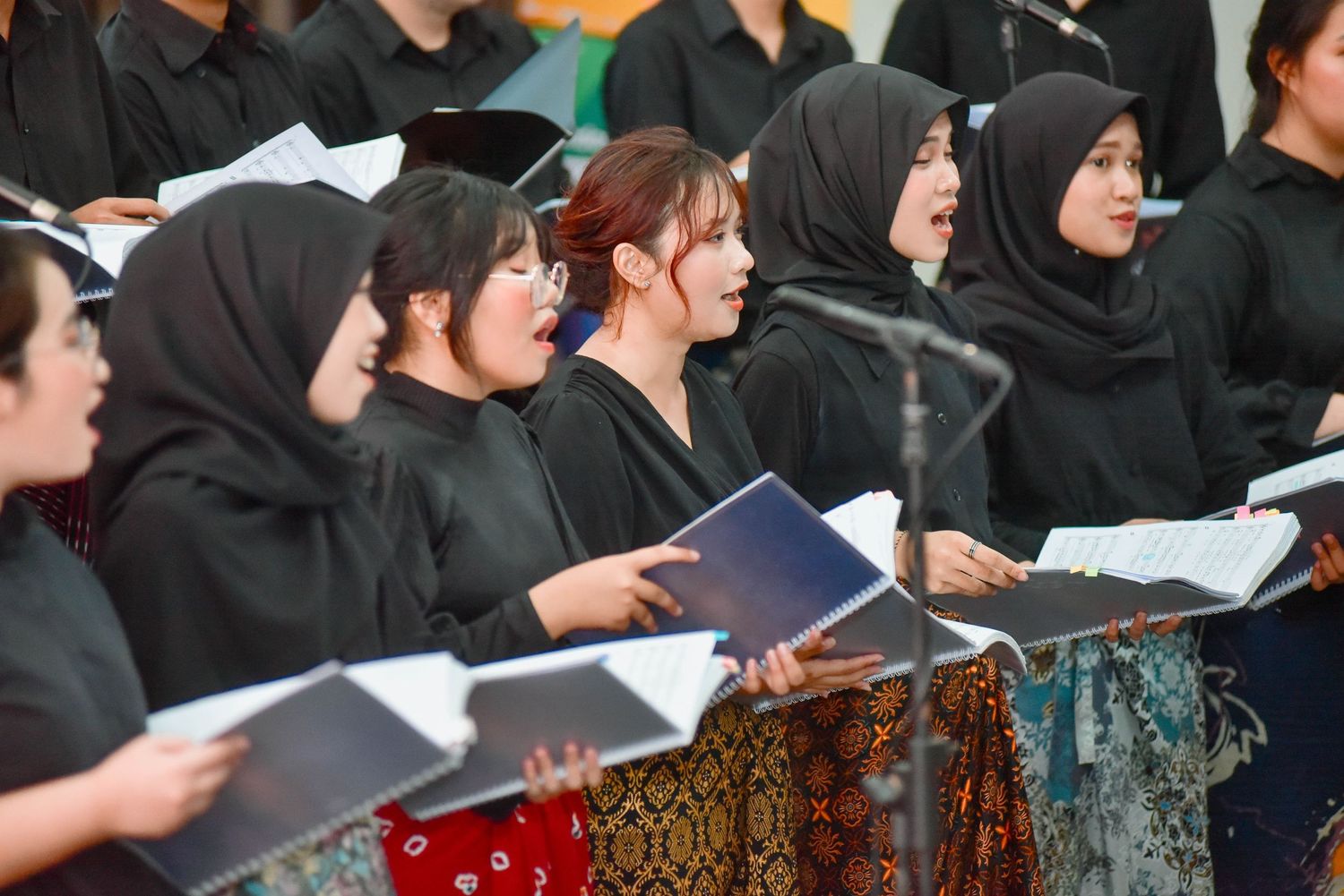 A group of people wearing black attire stand together while holding papers and books during a ceremony.