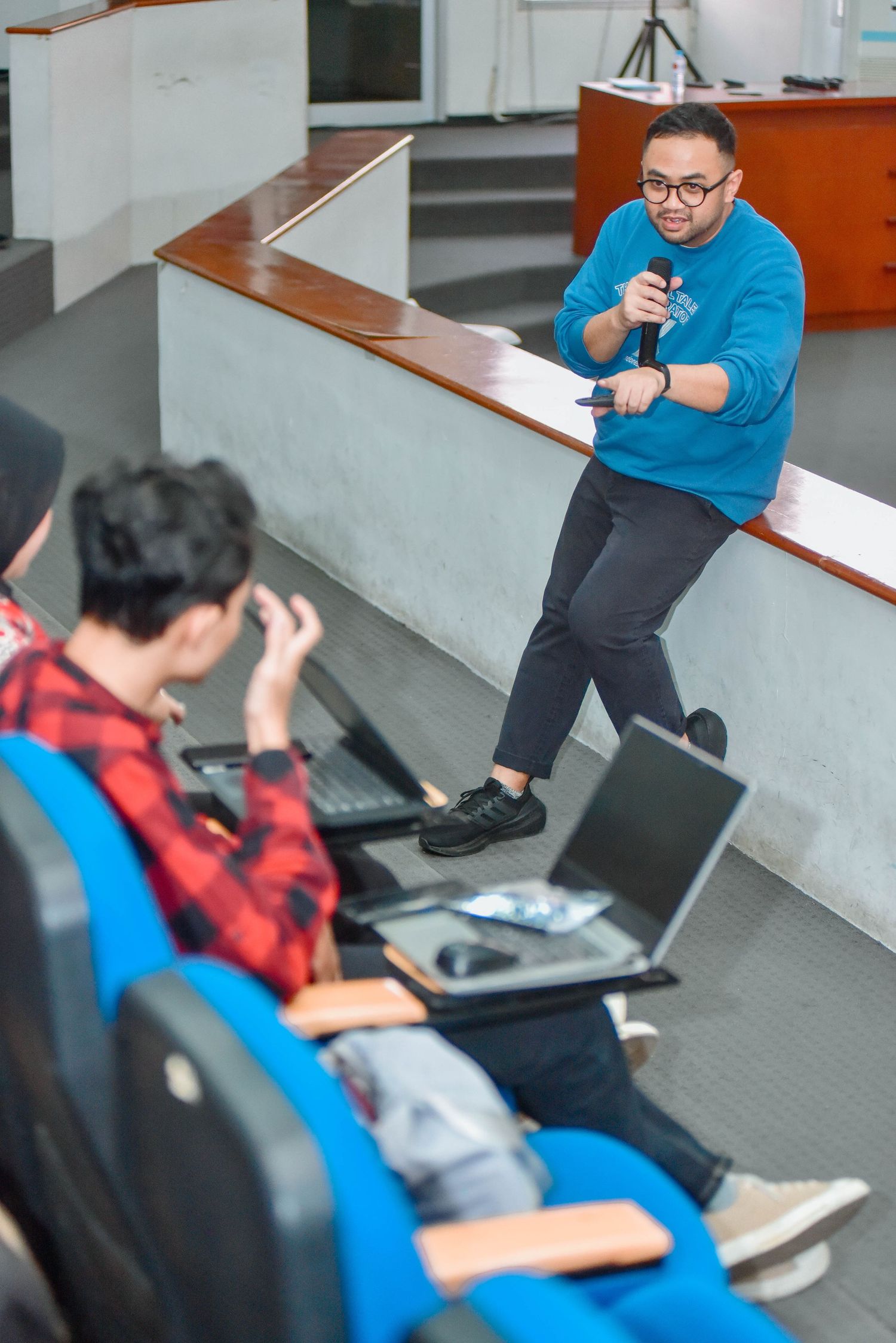 Students sitting on stairs collaborate on laptops and digital devices in a modern educational setting.